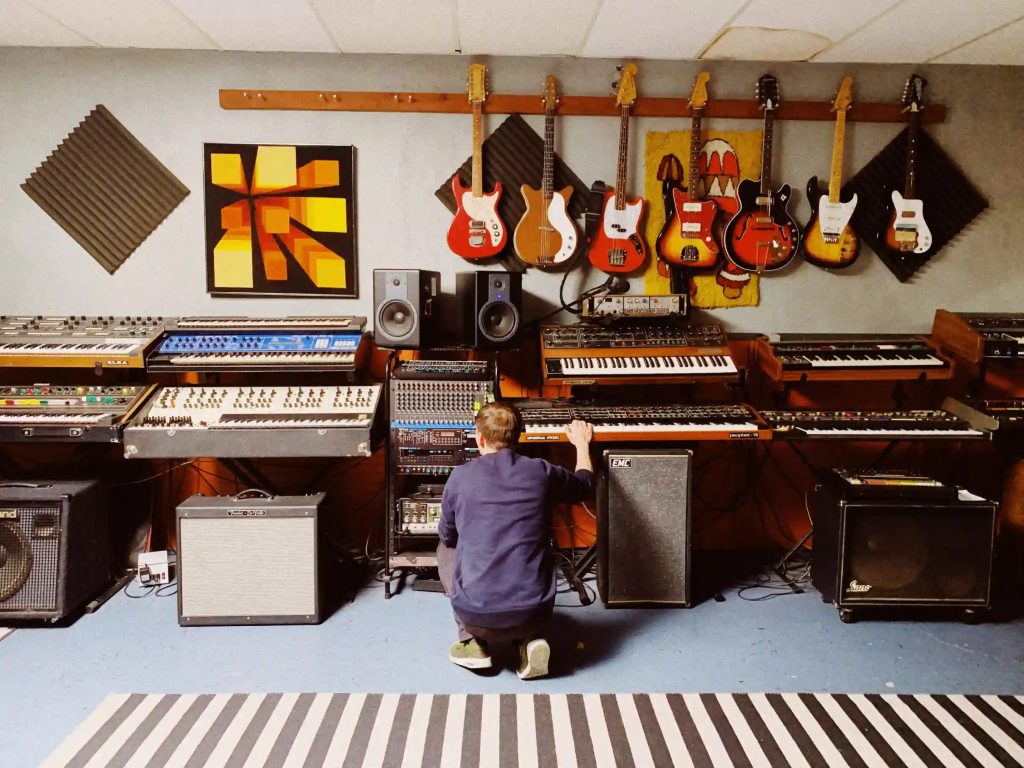 a wall of synthesizers in a home studio